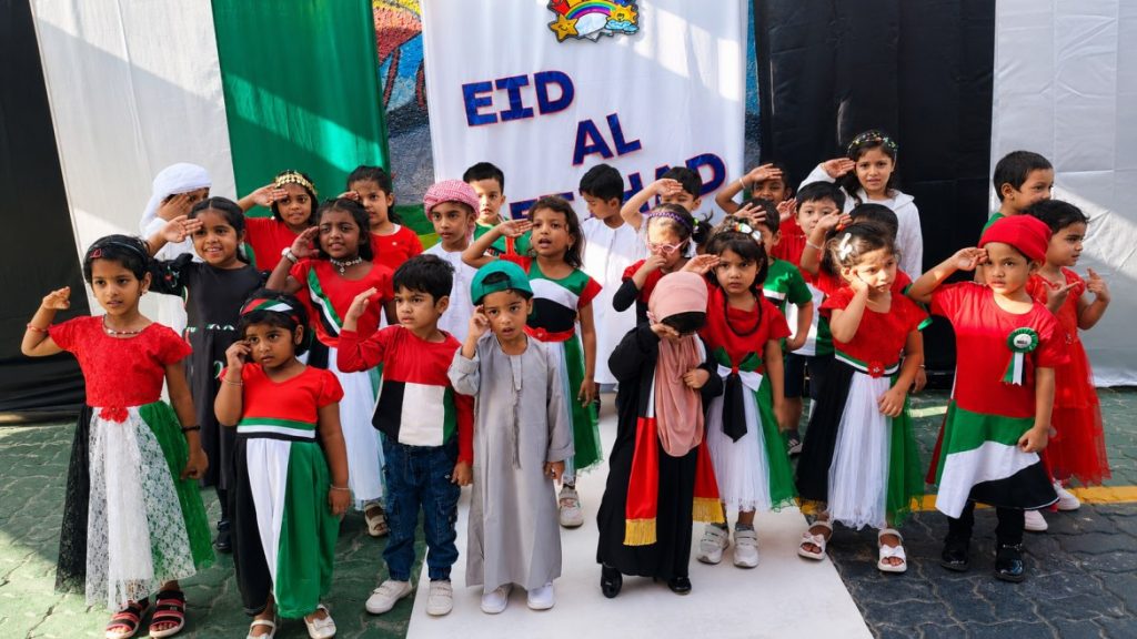 Children dressed in UAE national colours and traditional attire celebrating Eid Al Etihad at school.