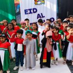 Children dressed in UAE national colours and traditional attire celebrating Eid Al Etihad at school.
